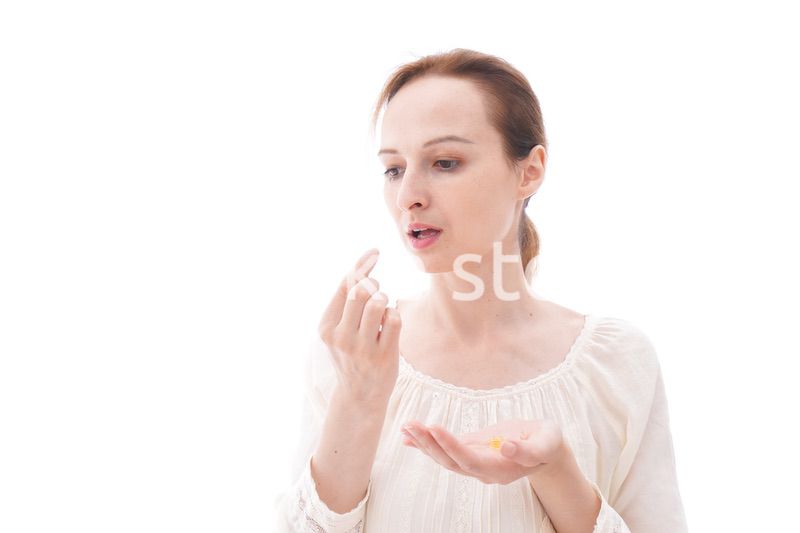 サプリメントを飲む笑顔の若い女性