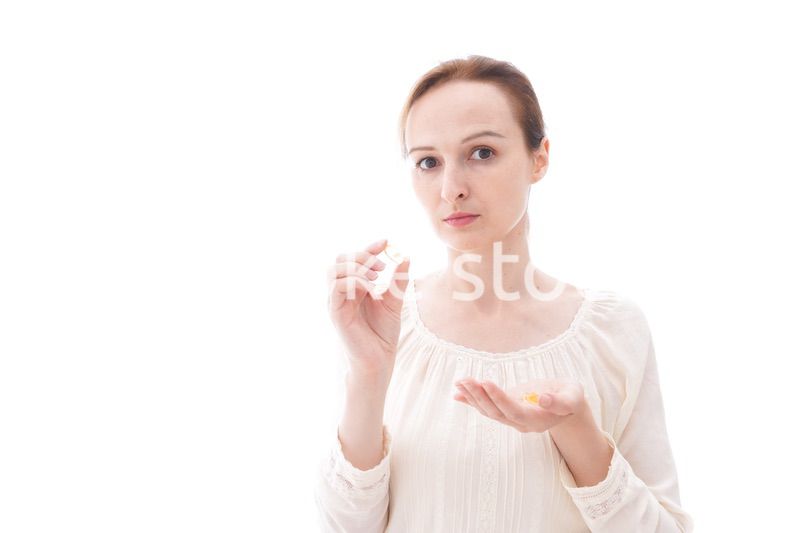 サプリメントを飲む笑顔の若い女性