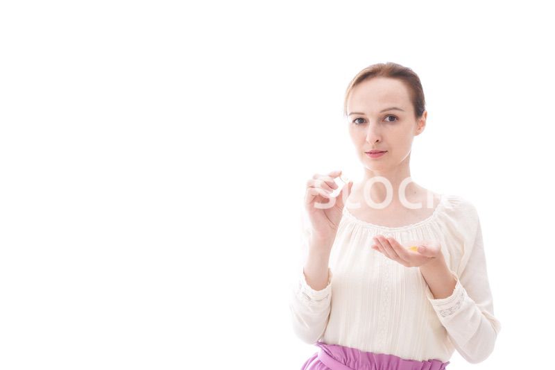 サプリメントを飲む笑顔の若い女性