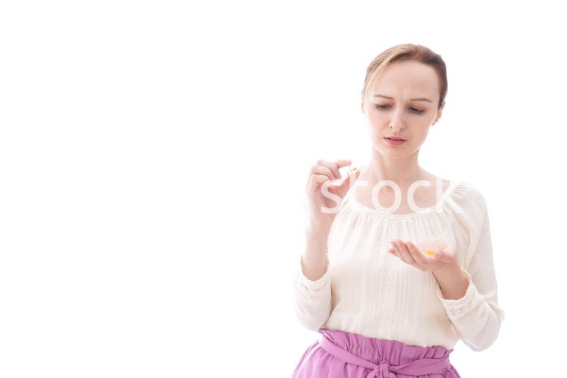 サプリメントを飲む笑顔の若い女性