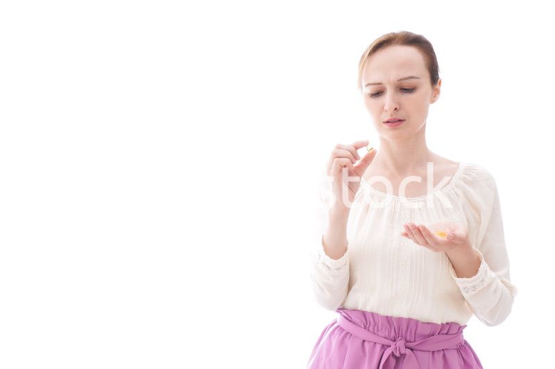 サプリメントを飲む笑顔の若い女性