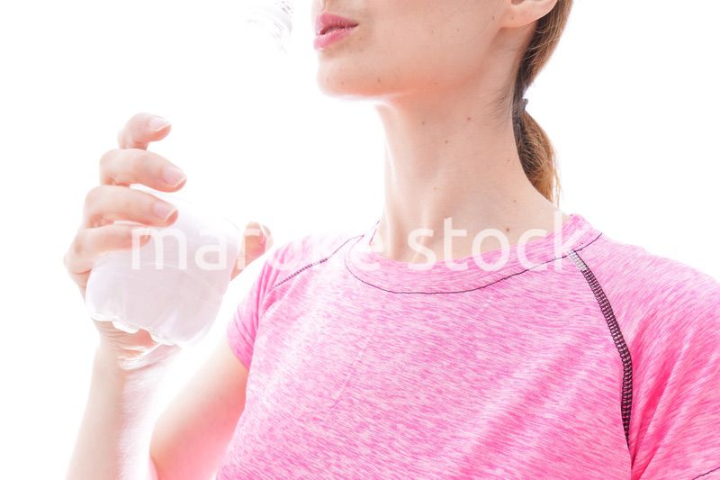 水分補給をするスポーツウェアを着た若い女性