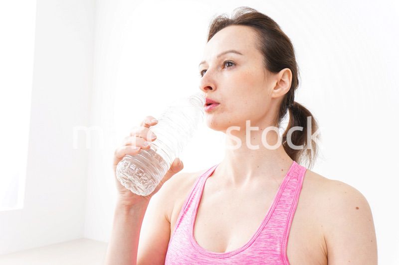 スポーツウェアを着て水分補給をする外国人の女性