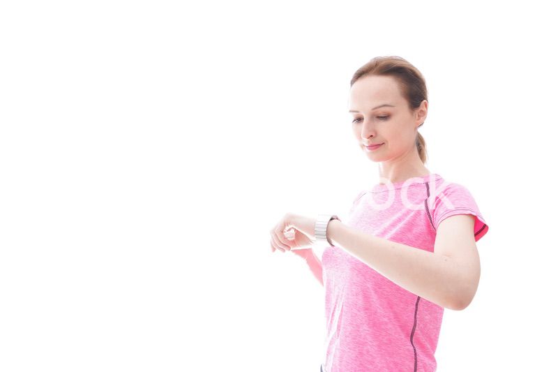 スマートウォッチを確認するスポーツウェアを着た若い女性