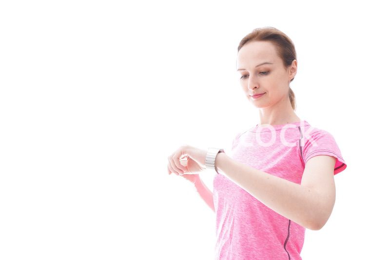 スマートウォッチを確認するスポーツウェアを着た若い女性