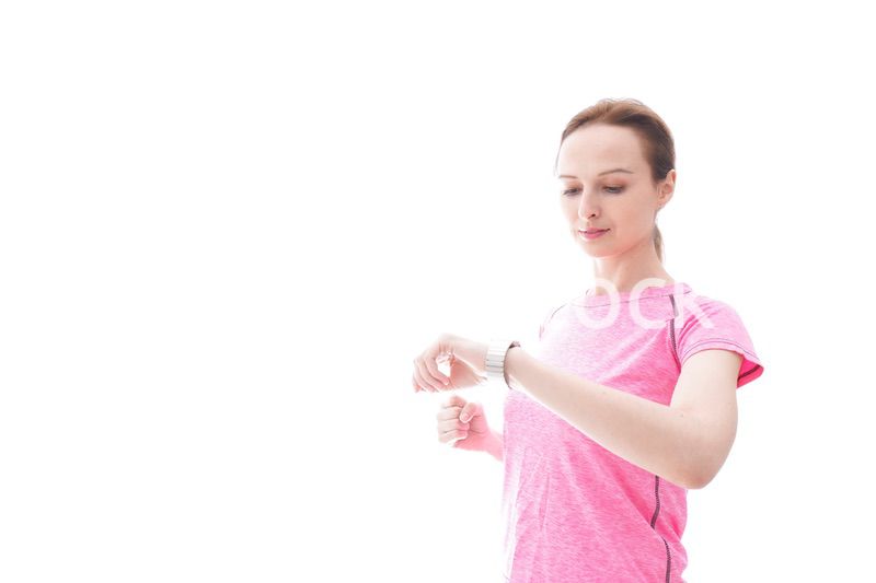 スマートウォッチを確認するスポーツウェアを着た若い女性