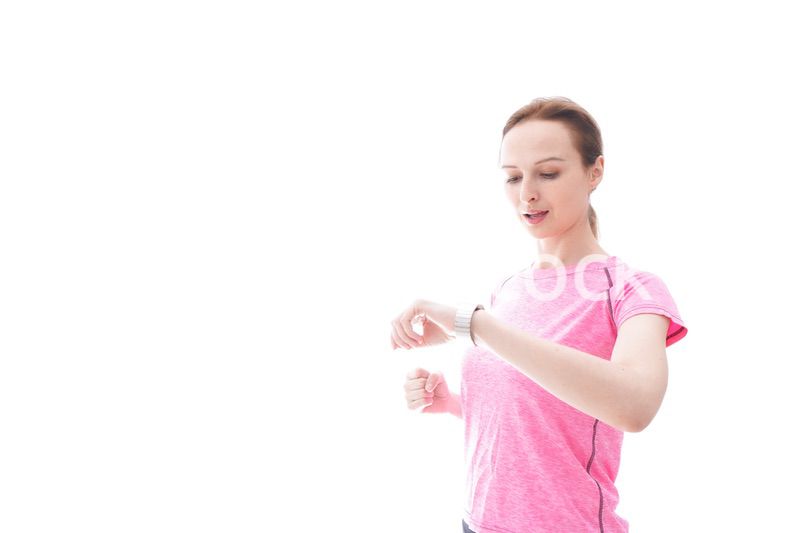 スマートウォッチを確認するスポーツウェアを着た若い女性