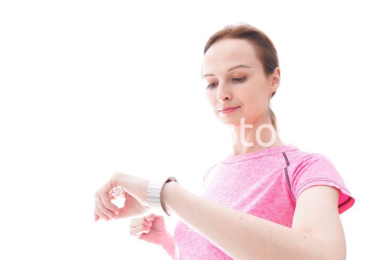 スマートウォッチを確認するスポーツウェアを着た若い女性