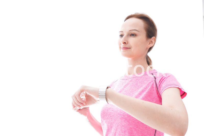 スマートウォッチを確認するスポーツウェアを着た若い女性