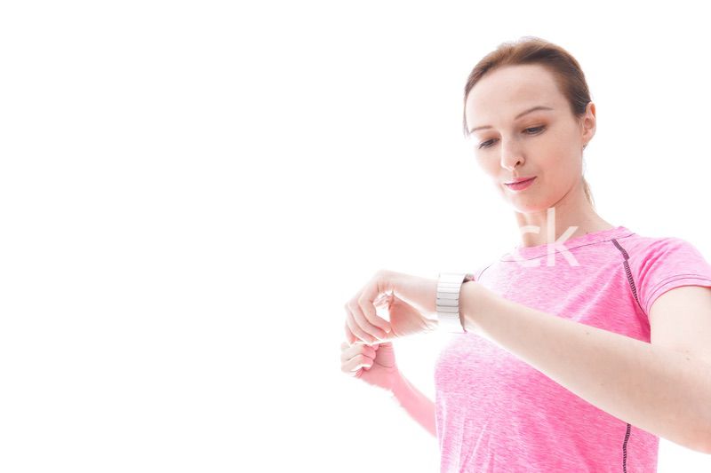 スマートウォッチを確認するスポーツウェアを着た若い女性