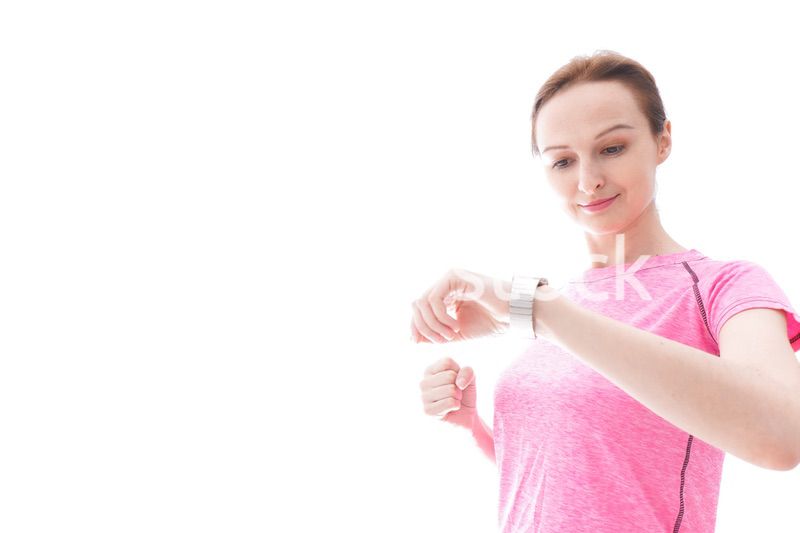 スマートウォッチを確認するスポーツウェアを着た若い女性