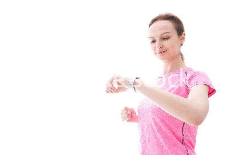 スマートウォッチを確認するスポーツウェアを着た若い女性