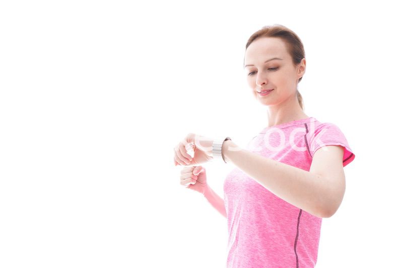 スマートウォッチを確認するスポーツウェアを着た若い女性