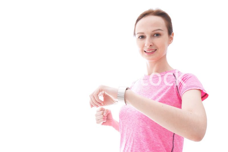 スマートウォッチを確認するスポーツウェアを着た若い女性