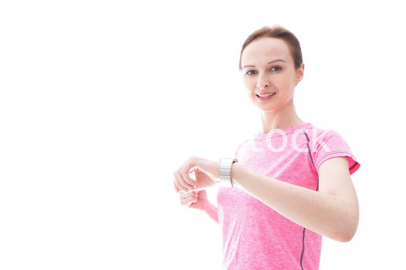 スマートウォッチを確認するスポーツウェアを着た若い女性