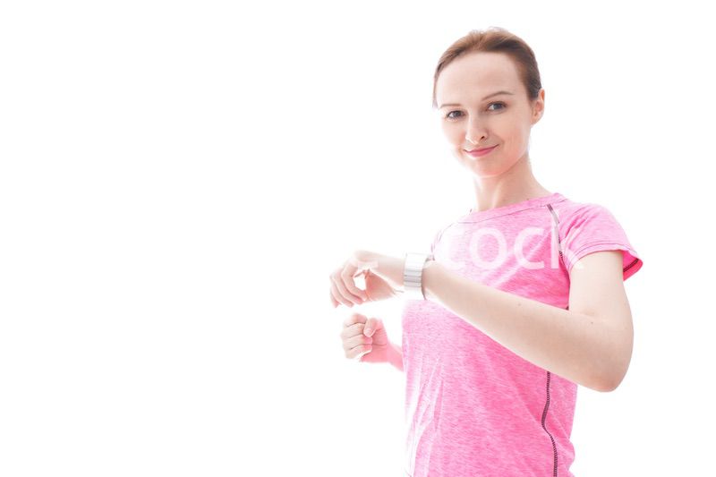 スマートウォッチを確認するスポーツウェアを着た若い女性