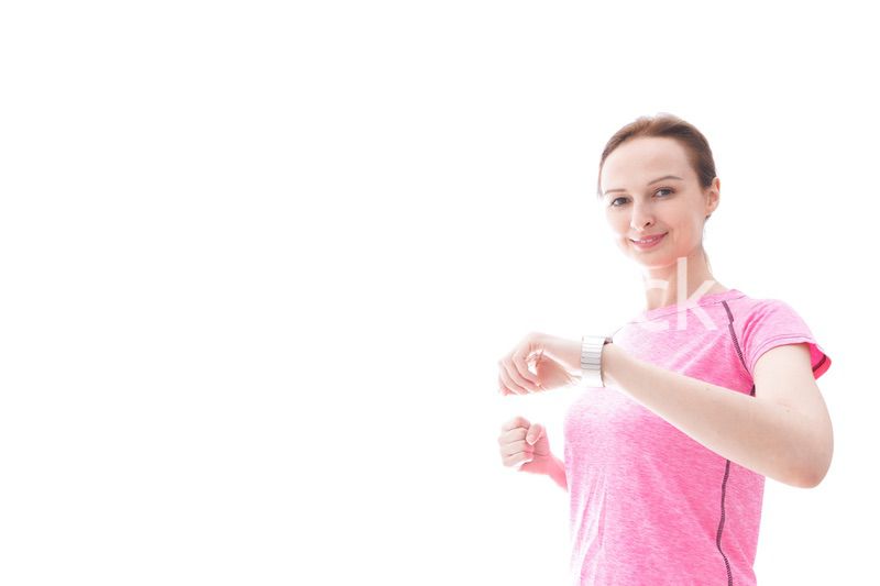 スマートウォッチを確認するスポーツウェアを着た若い女性