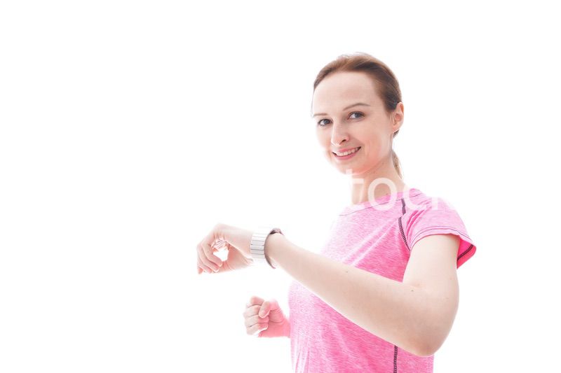 スマートウォッチを確認するスポーツウェアを着た若い女性