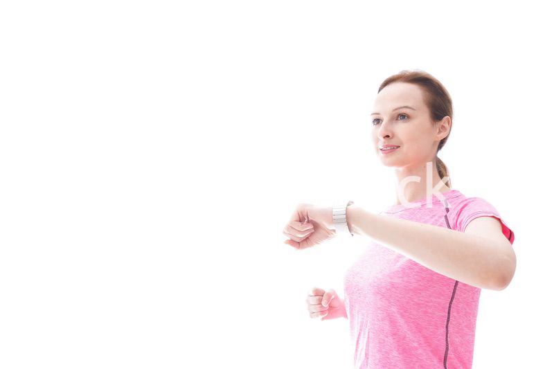 スマートウォッチを確認するスポーツウェアを着た若い女性