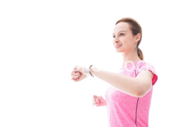 スマートウォッチを確認するスポーツウェアを着た若い女性