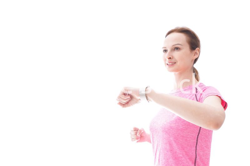 スマートウォッチを確認するスポーツウェアを着た若い女性