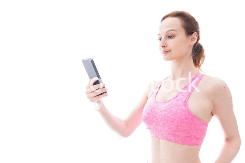 スマホを使うスポーツウェアを着た若い女性