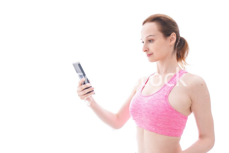 スマホを使うスポーツウェアを着た若い女性