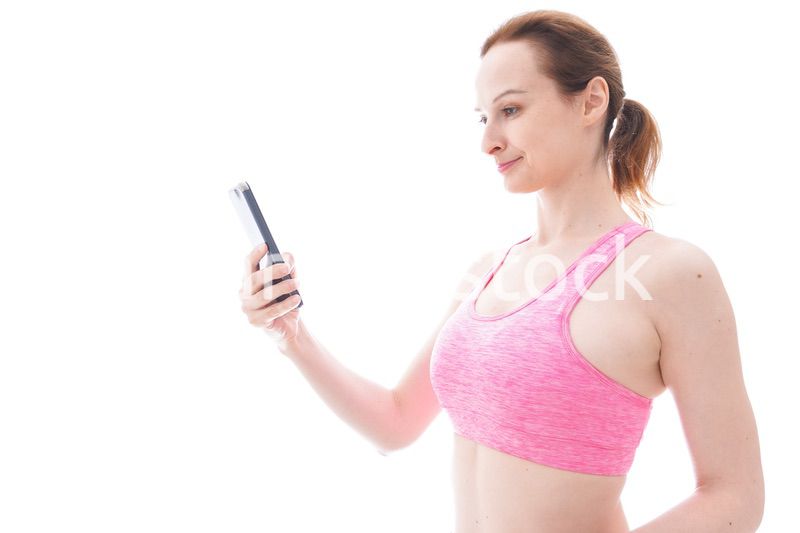 スマホを使うスポーツウェアを着た若い女性