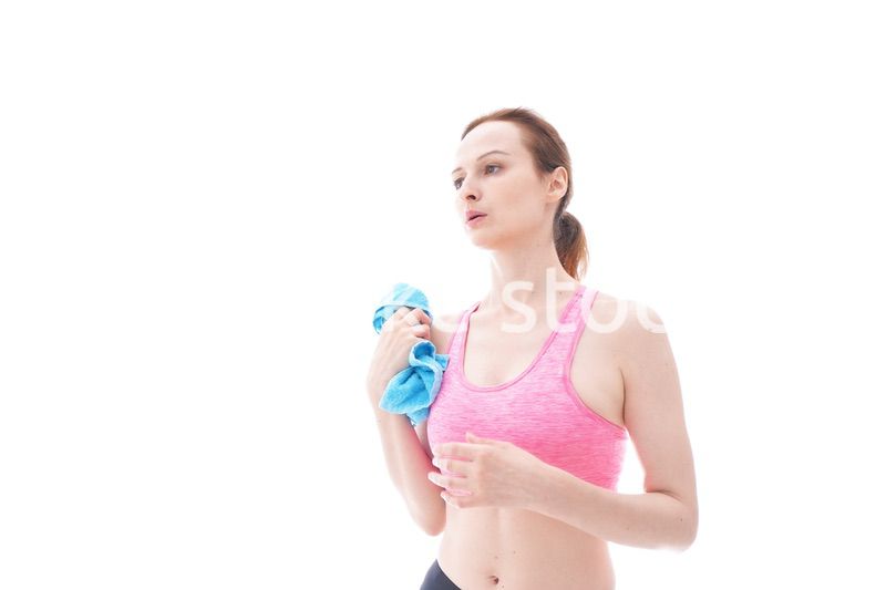 汗を拭くスポーツウェアを着た若い女性