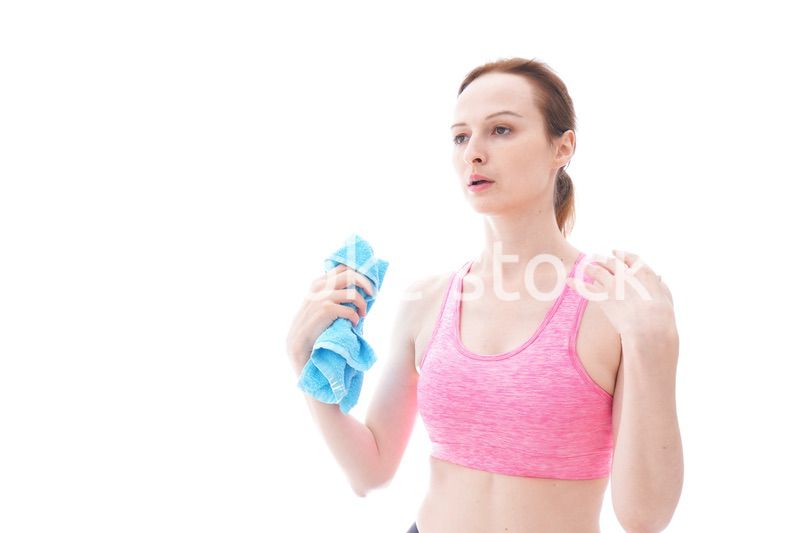 汗を拭くスポーツウェアを着た若い女性