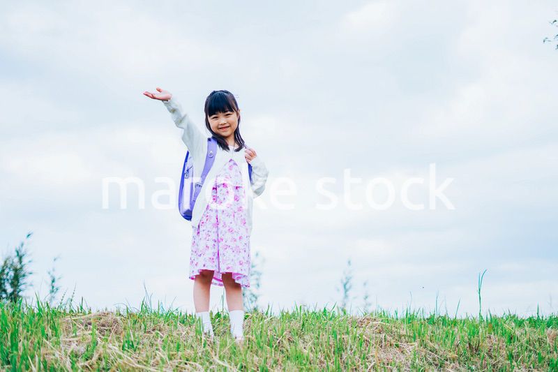 ランドセルを背負って手を振る小さな女の子