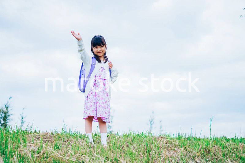 ランドセルを背負って手を振る小さな女の子