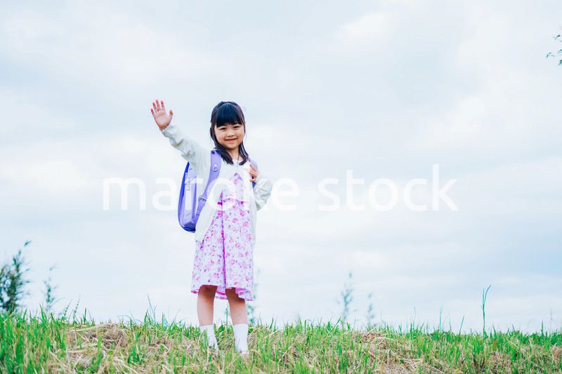 ランドセルを背負って手を振る小さな女の子