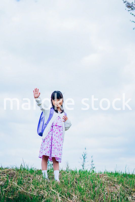 ランドセルを背負って手を振る小さな女の子