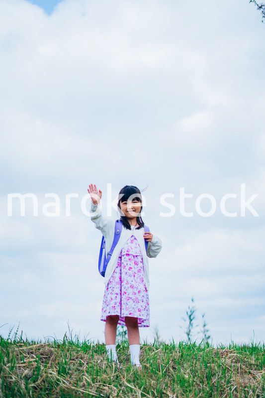 ランドセルを背負って手を振る小さな女の子