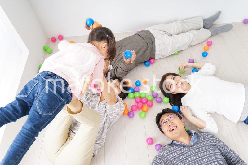 部屋で寝転ぶ三世代の家族