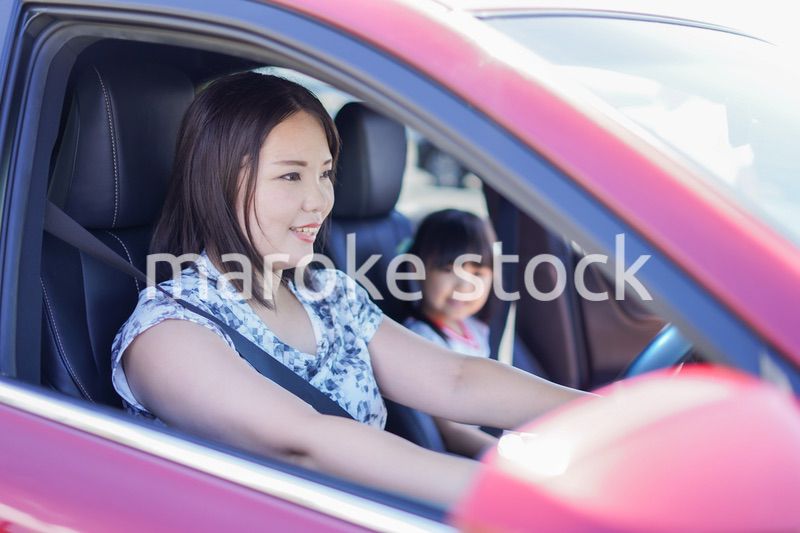 お母さんと車に乗る小さな女の子