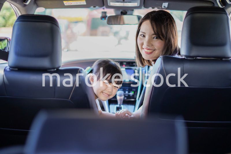お母さんと車に乗る小さな女の子