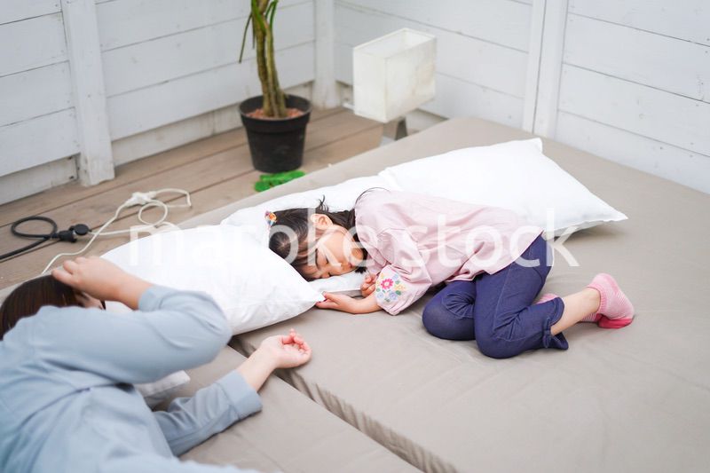 お昼寝をする小学生の女の子とお母さん