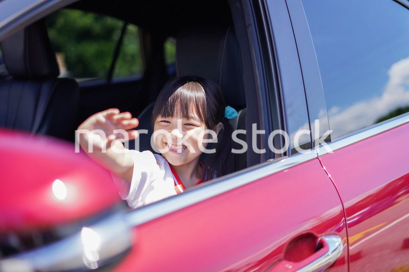 車から手を振る小さな女の子