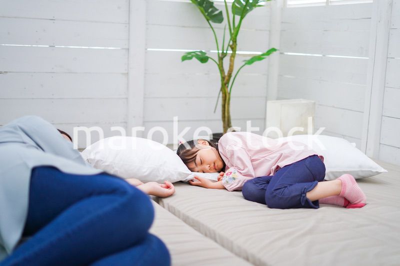 お昼寝をする小学生の女の子とお母さん