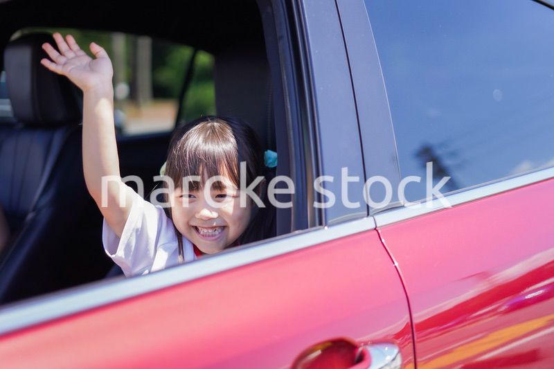 車から手を振る小さな女の子