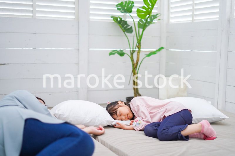 お昼寝をする小学生の女の子とお母さん