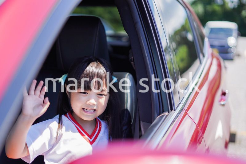 車から手を振る小さな女の子