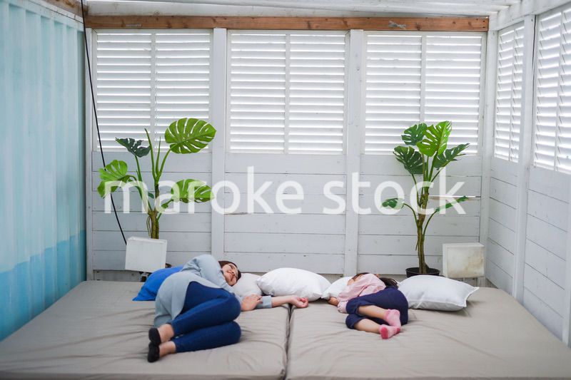 お昼寝をする小学生の女の子とお母さん