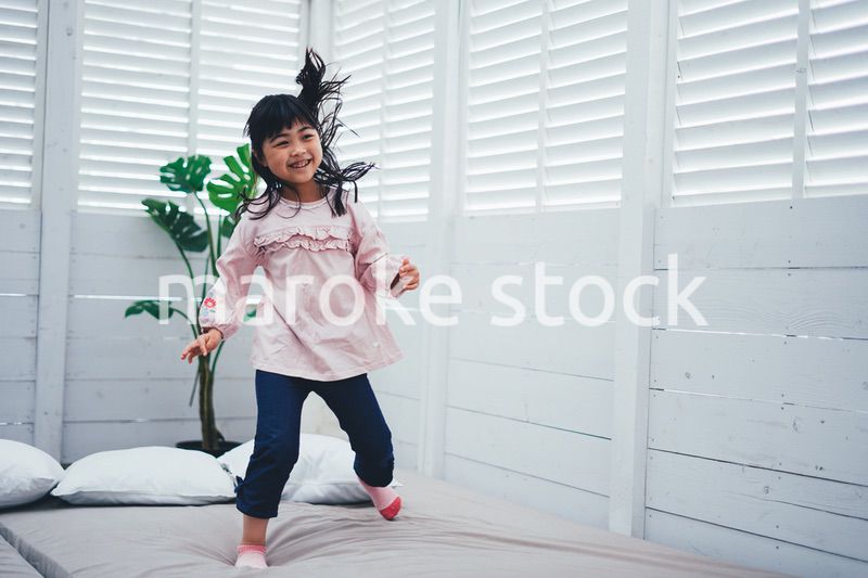 ベッドでジャンプをする小さな女の子
