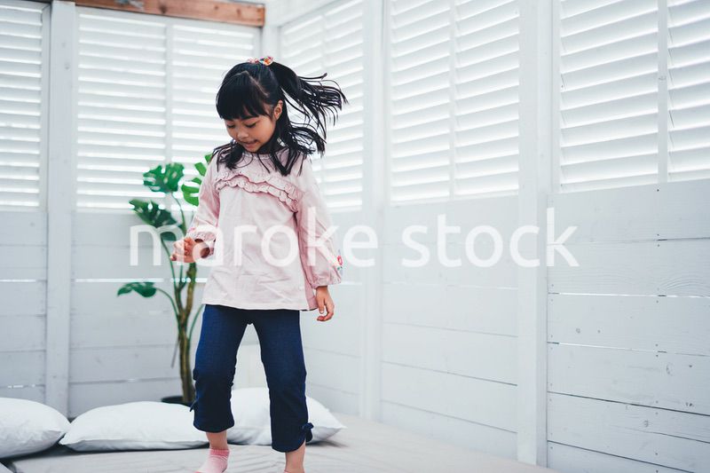 ベッドでジャンプをする小さな女の子