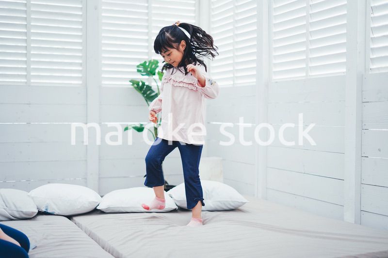 ベッドでジャンプをする小さな女の子