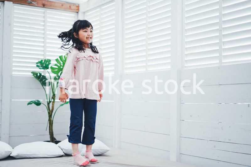 ベッドでジャンプをする小さな女の子