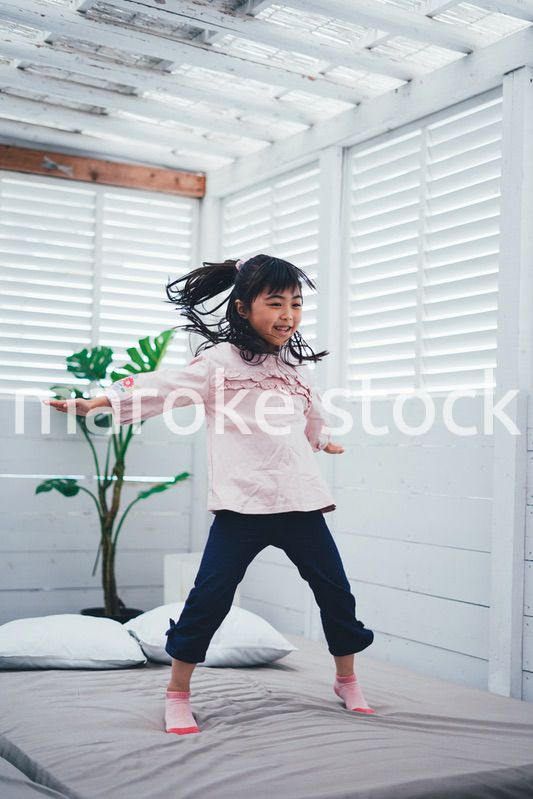ベッドでジャンプをする小さな女の子